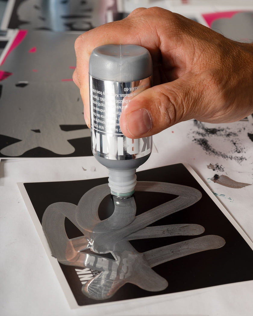 Krink k-60 paint marker being used on sticker in silver ink