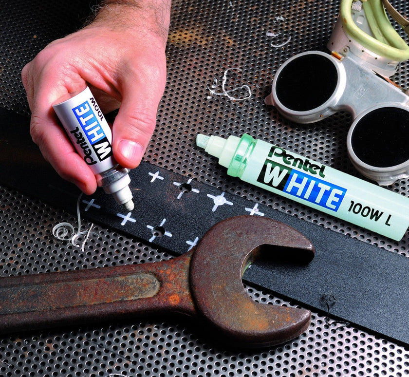 White pentel 100w drawing crosses on black metal surface beside wrench and welding tools