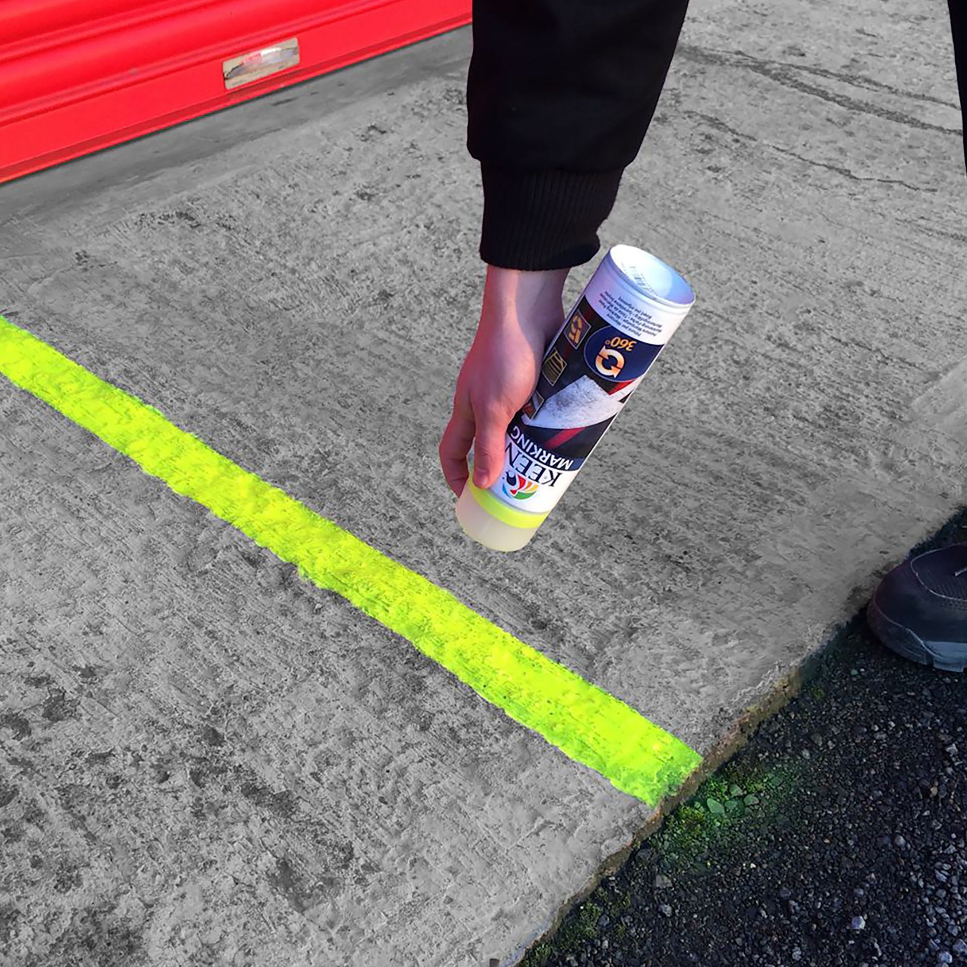 Can of yellow Keen Line Marking Spray Paint being sprayed on tarmac