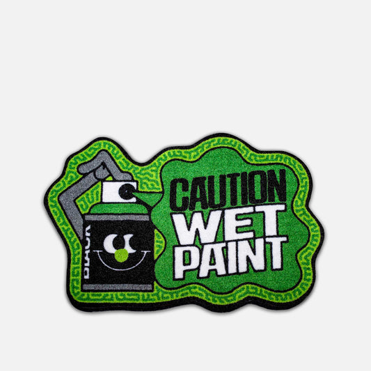 Caution wet paint sign with green border and black spray can icon on a grey background